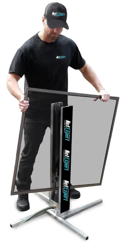 Technicien de Moustiquaire Net Expert préparant un panneau sur son support d'atelier mobile